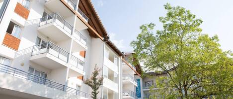 A multi-story building with balconies, arched windows, and a clear sky.