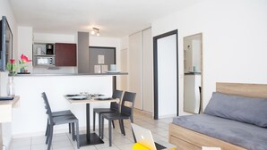 Un espacio habitable moderno y compacto con comedor, kitchenette y sofá.