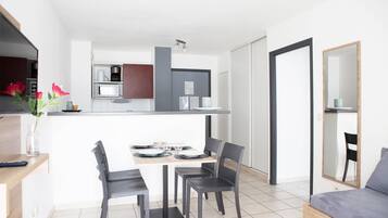 A modern kitchen with a dining area, a bed, and a mirror.