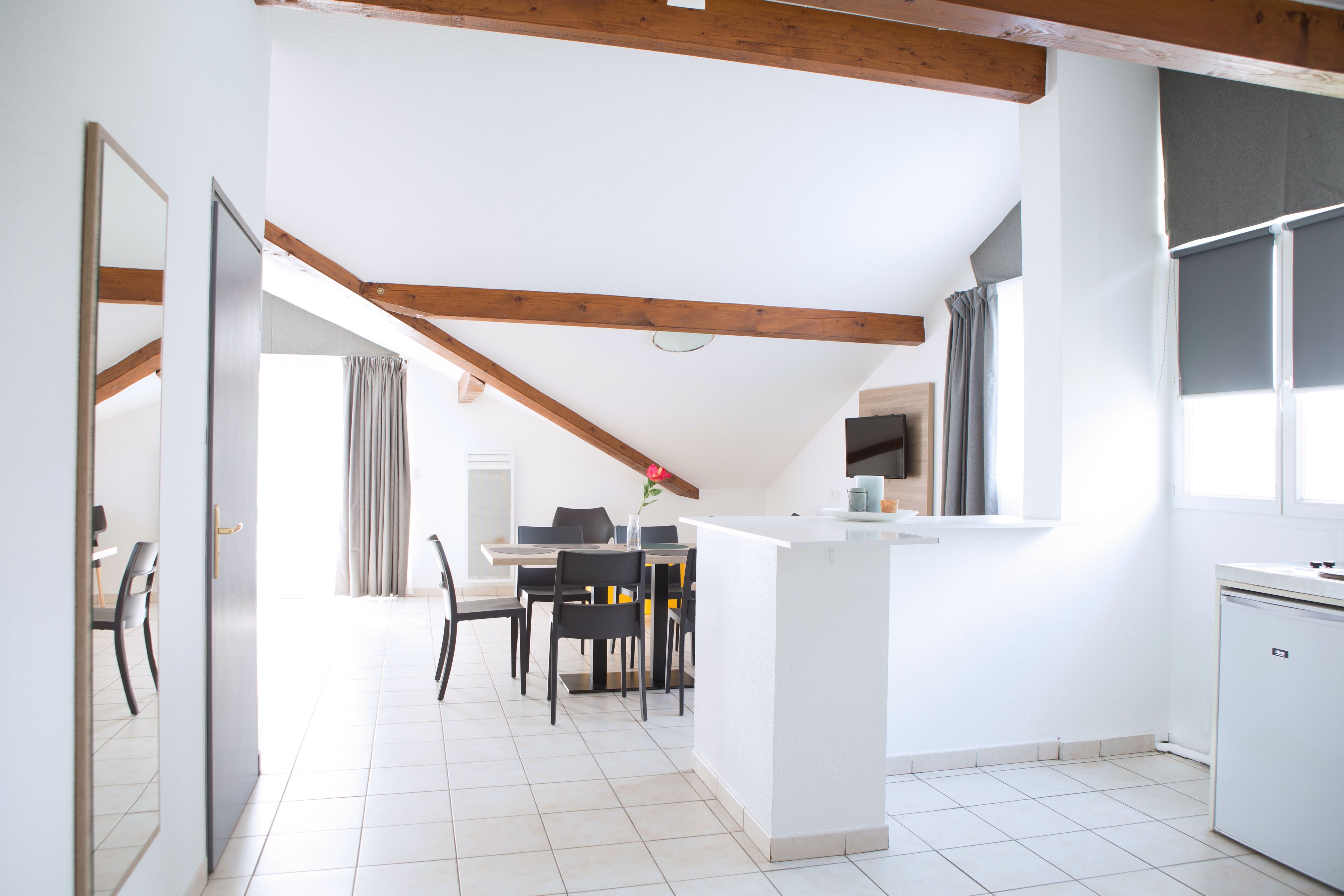 A modern kitchen with white cabinetry, a central island, and a dining area with a table and chairs.