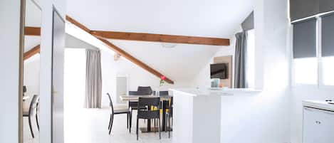 Une cuisine moderne avec des meubles blancs, un îlot central et un coin repas comprenant une table et des chaises.