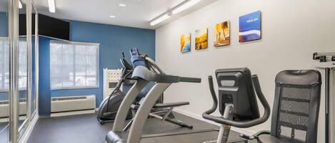 Un gimnasio con cintas de correr, una banca de pesas y equipamiento de ejercicio.
