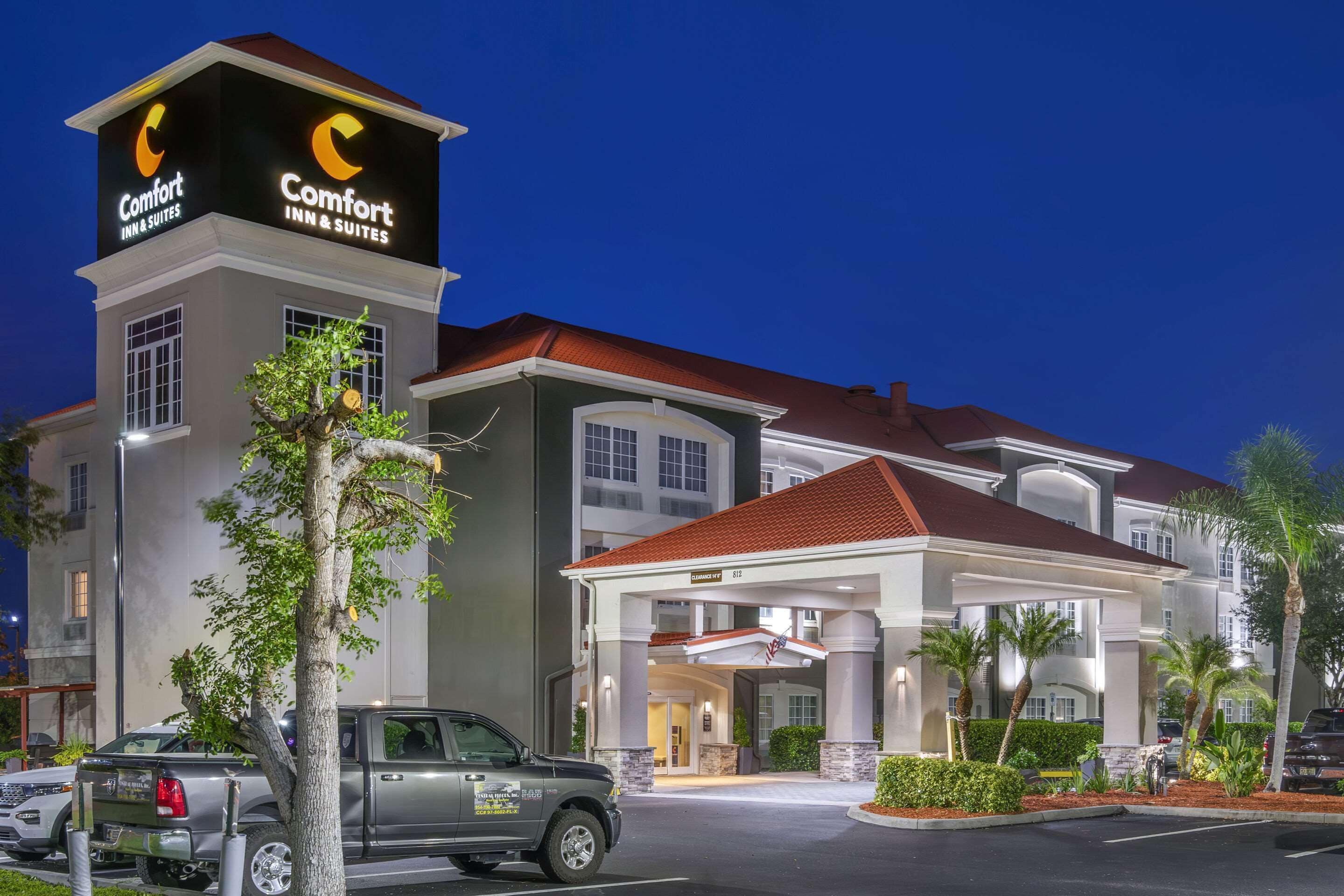 A Comfort Inn & Suites hotel with a prominent sign, a covered entrance, and a parking area with a truck.