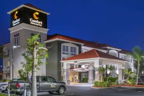 A Comfort Inn & Suites hotel with a prominent sign, a covered entrance, and a parking area with a truck. - Comfort Inn & Suites (Port Charlotte)