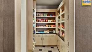A narrow pantry with shelves stocked with various food items and a sign indicating it's part of the Bright Side Market. - Comfort Inn & Suites (Port Charlotte)