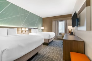 A hotel room with two beds, a desk with a chair, a television, and a large window with curtains. - Comfort Inn & Suites (Port Charlotte)