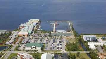 An aerial view of a coastal hotel with multiple parking lots, a marina, and a large building with a green roof.