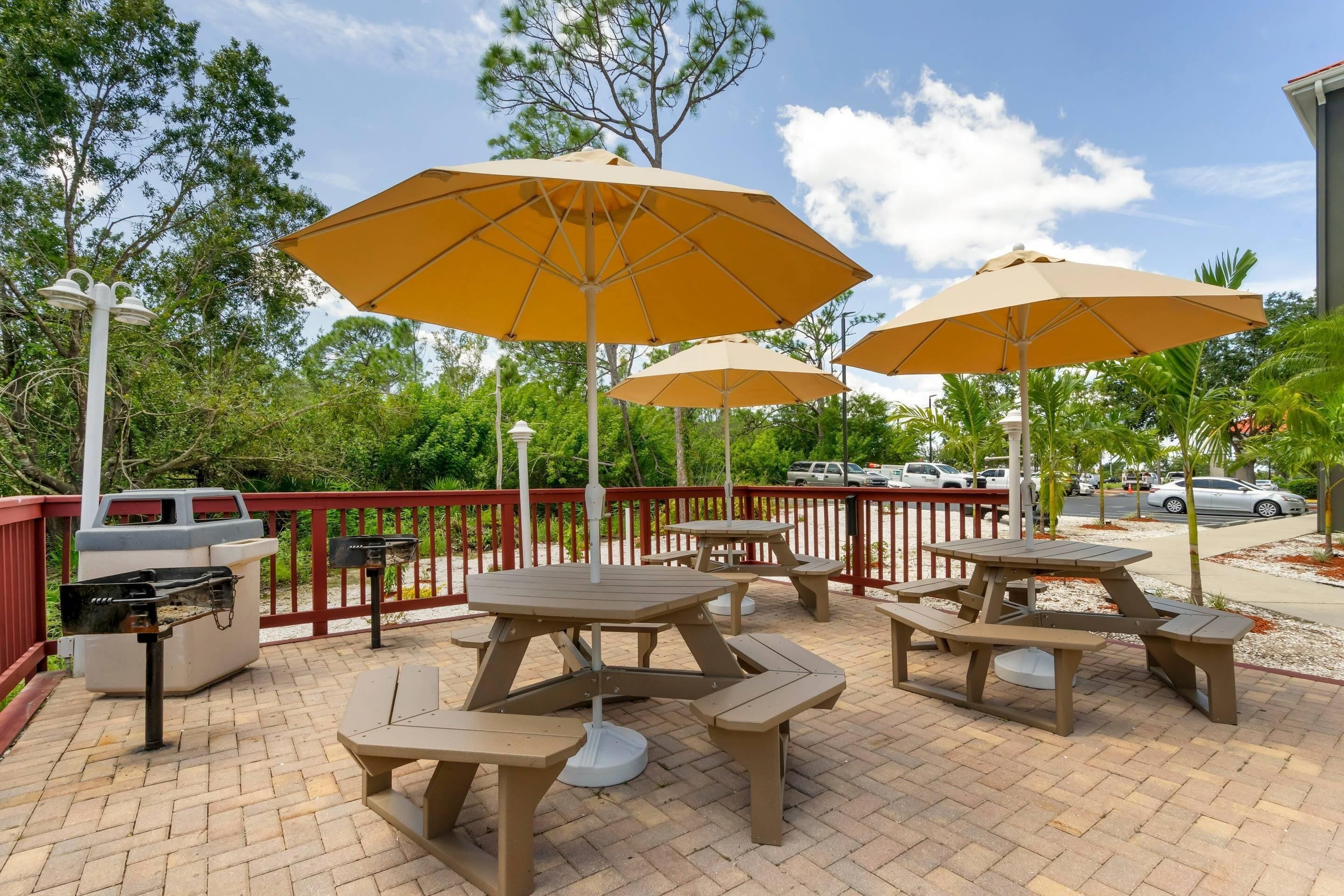 Outdoor patio furniture with tables and benches, surrounded by a red railing.