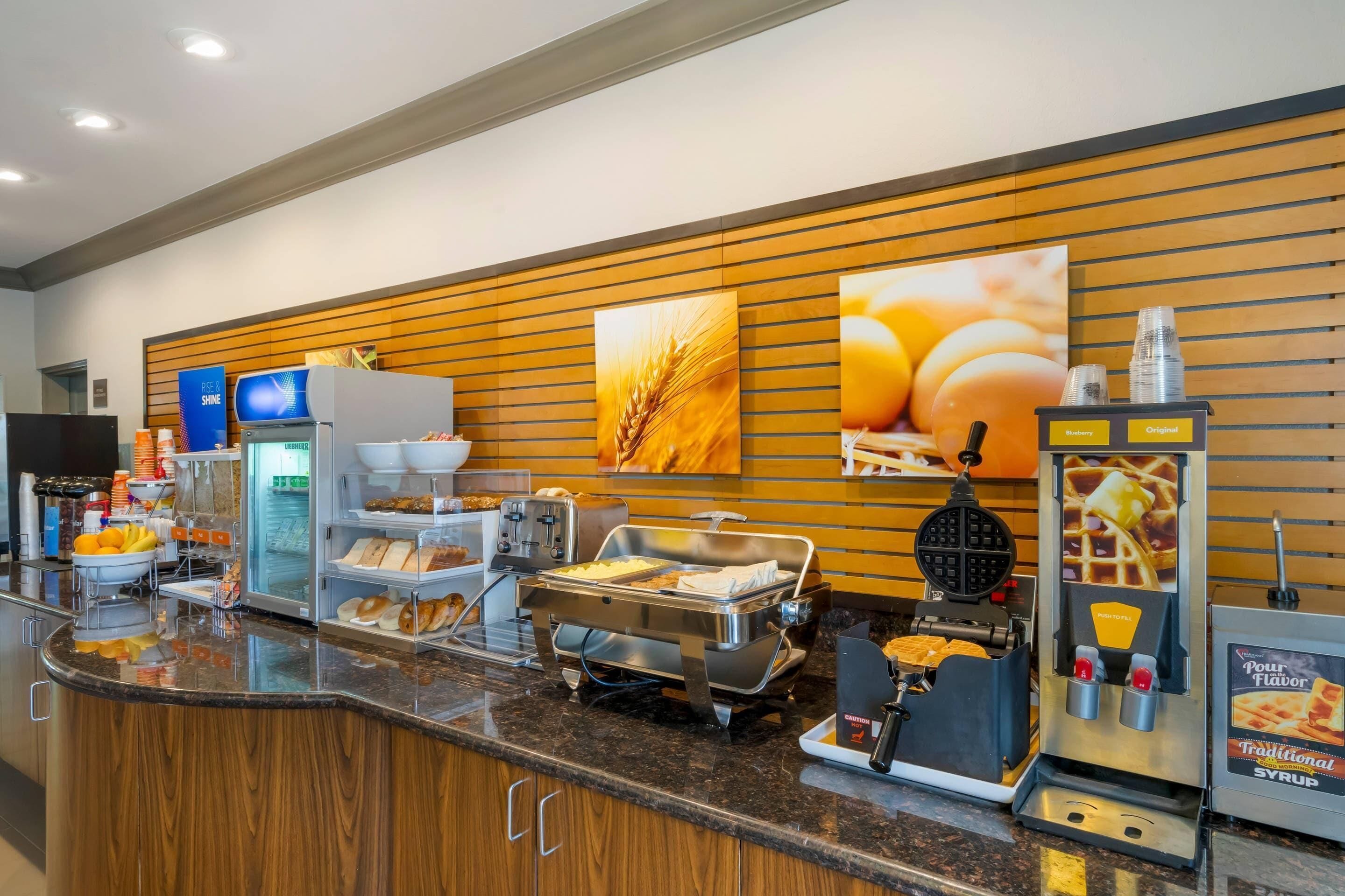 Ein Frühstücksbuffet mit verschiedenen Speisen und einer Waffelmaschine.