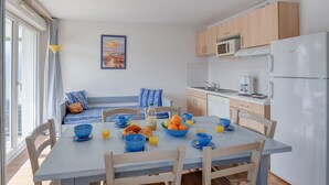 A modern kitchen with a dining area, featuring a breakfast setup with fruits, croissants, and beverages. - Résidence Les Jardins de l'Amirauté - Vacancéole (Les Sables-d'Olonne)