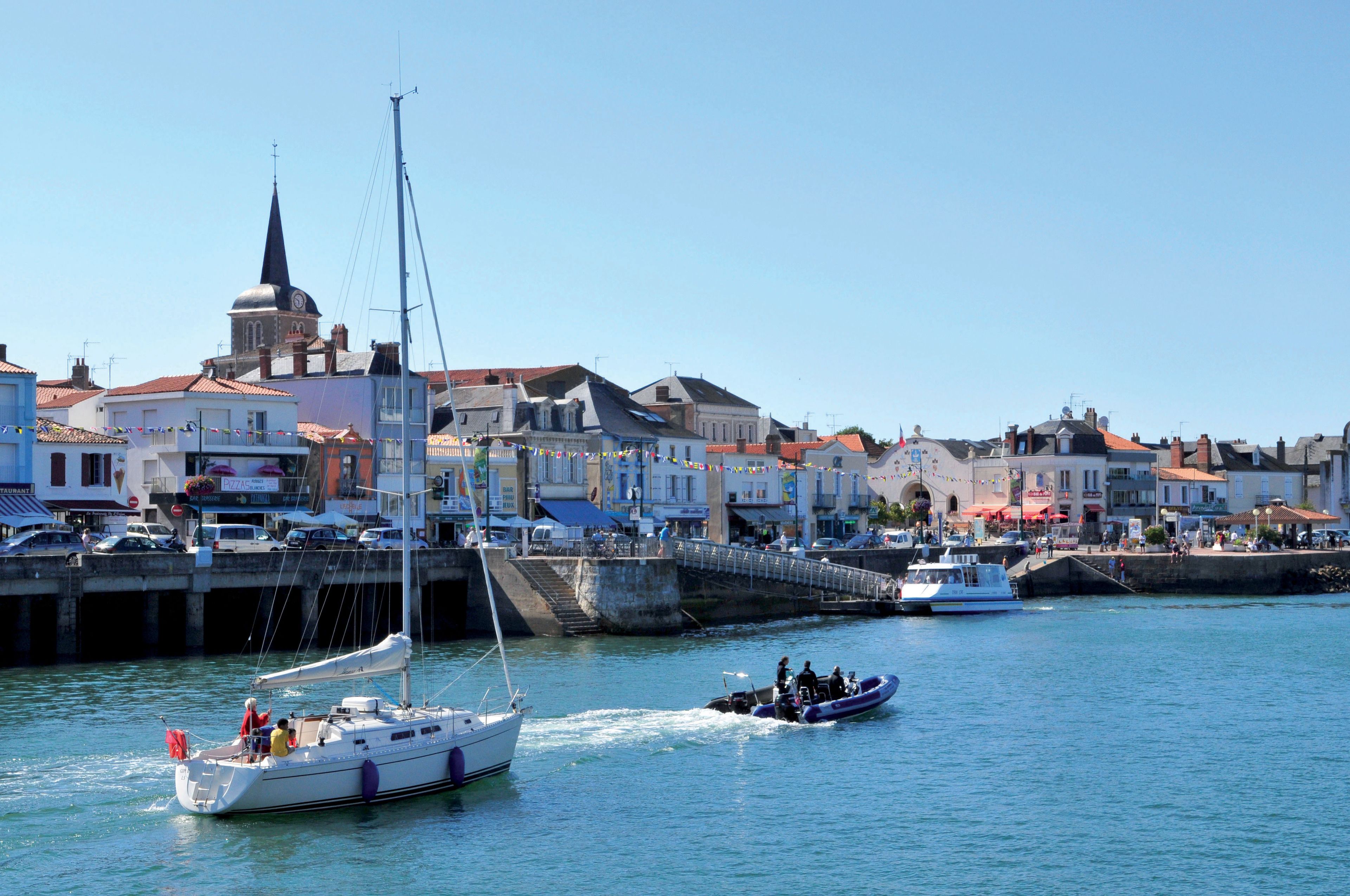 A harbor with boats, a bridge, and buildings with a church steeple.
