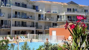 A multi-story hotel with balconies, a swimming pool, and outdoor seating areas. - Résidence Les Jardins de l'Amirauté - Vacancéole (Les Sables-d'Olonne)