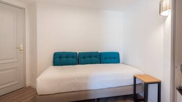 Un dormitorio con una cama, una mesita de noche y una puerta.