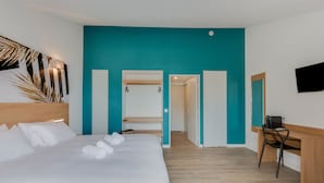 Una habitación de hotel moderna con una cama grande, un escritorio y una pared de acento color aguamarina.