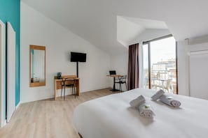 Une chambre d’hôtel avec un grand lit, un bureau avec une chaise, un téléviseur à écran plat et une fenêtre avec des rideaux.