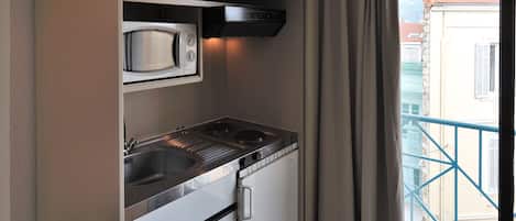 A compact kitchenette with a microwave, stove, and sink.
