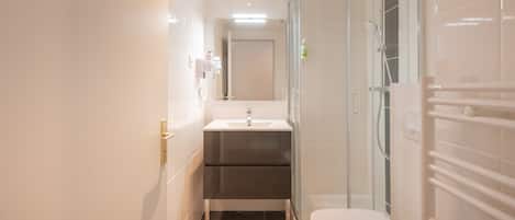 Uma casa de banho moderna com chuveiro, sanita e lavatório.