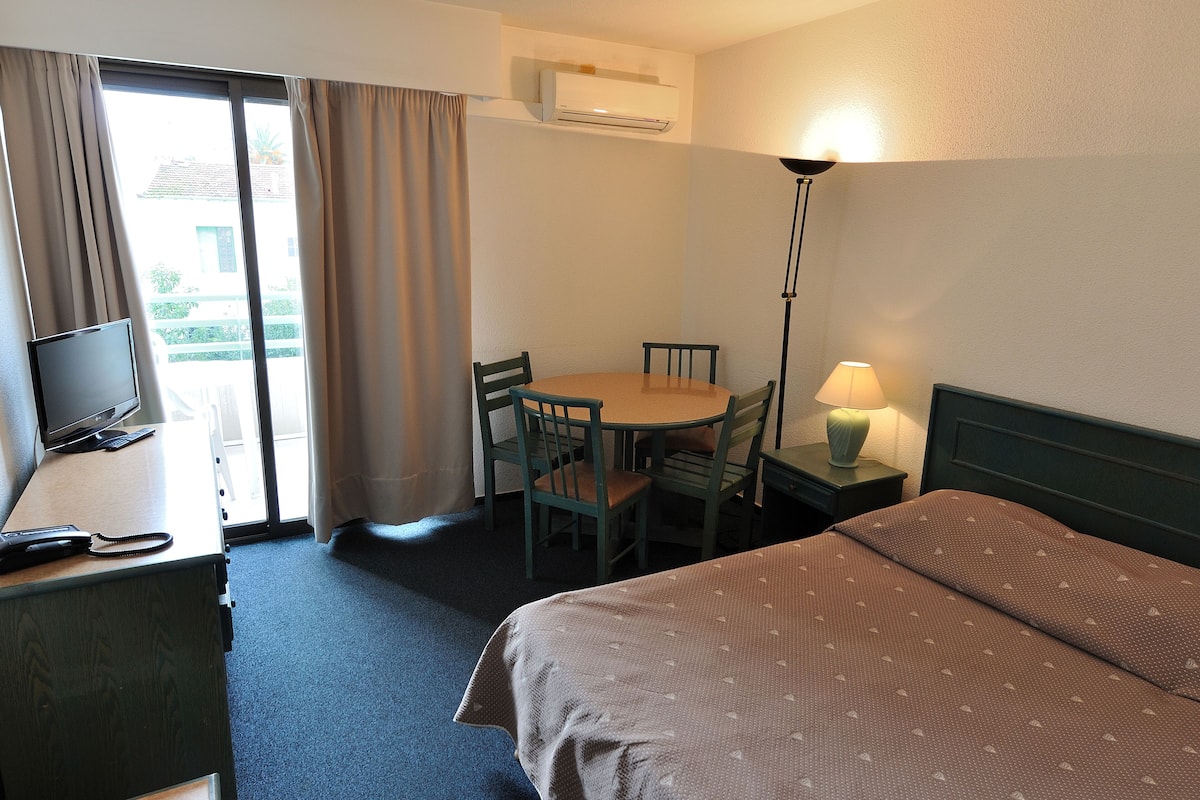 Une chambre d’hôtel comprenant un lit, un bureau avec une télévision, une chaise, une table et une lampe.