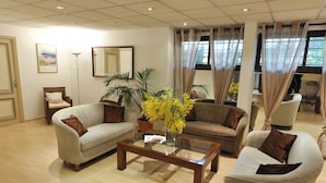 Amplia sala de estar con un gran ventanal, un sofá, una mesa de centro y un sillón.