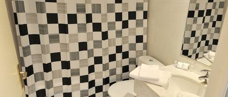 Un baño con cortina de ducha a cuadros, un inodoro y un lavabo con espejo.