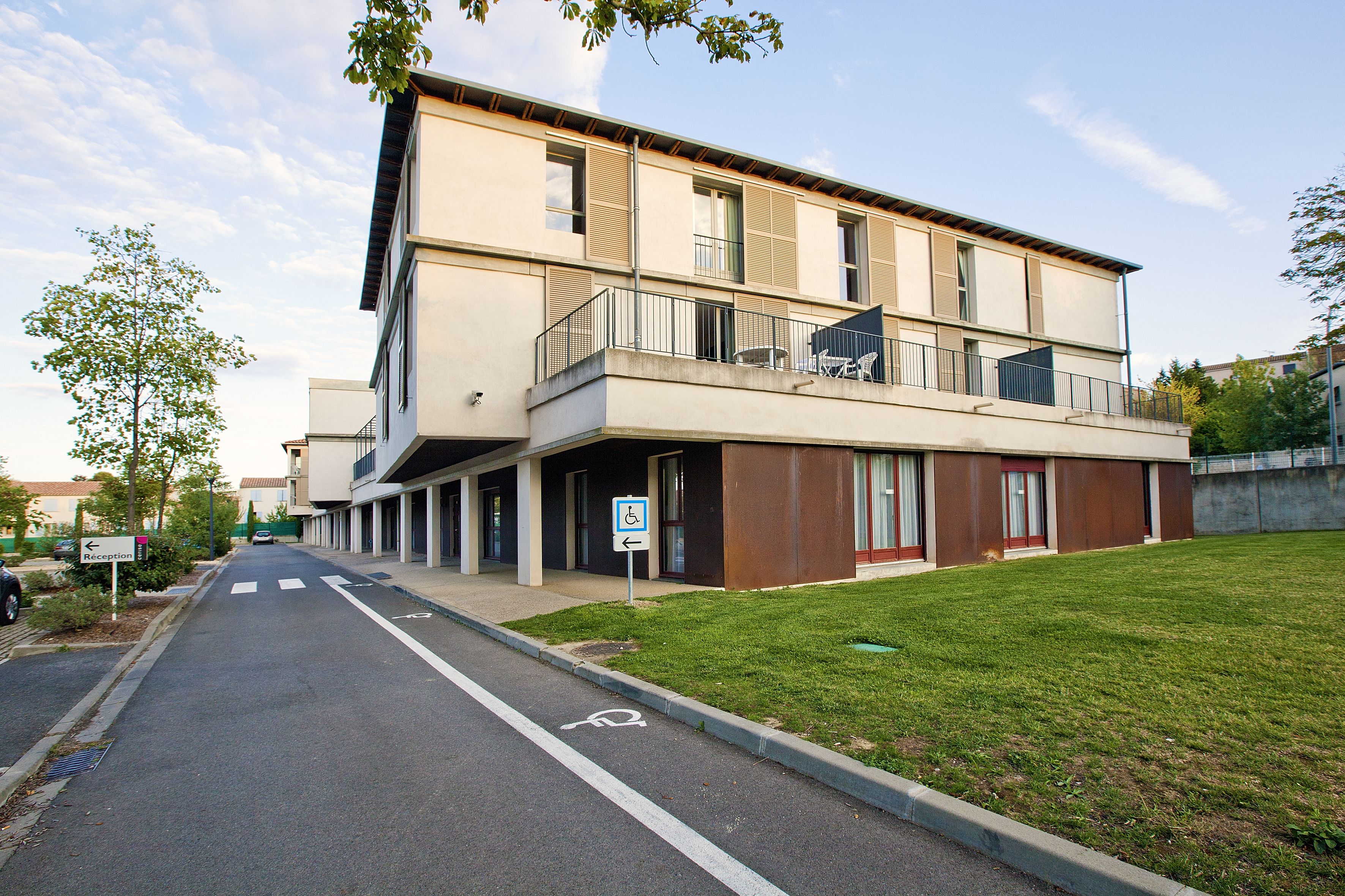 Un edificio moderno con techo plano, un balcón y un cartel que indica la zona de recepción.