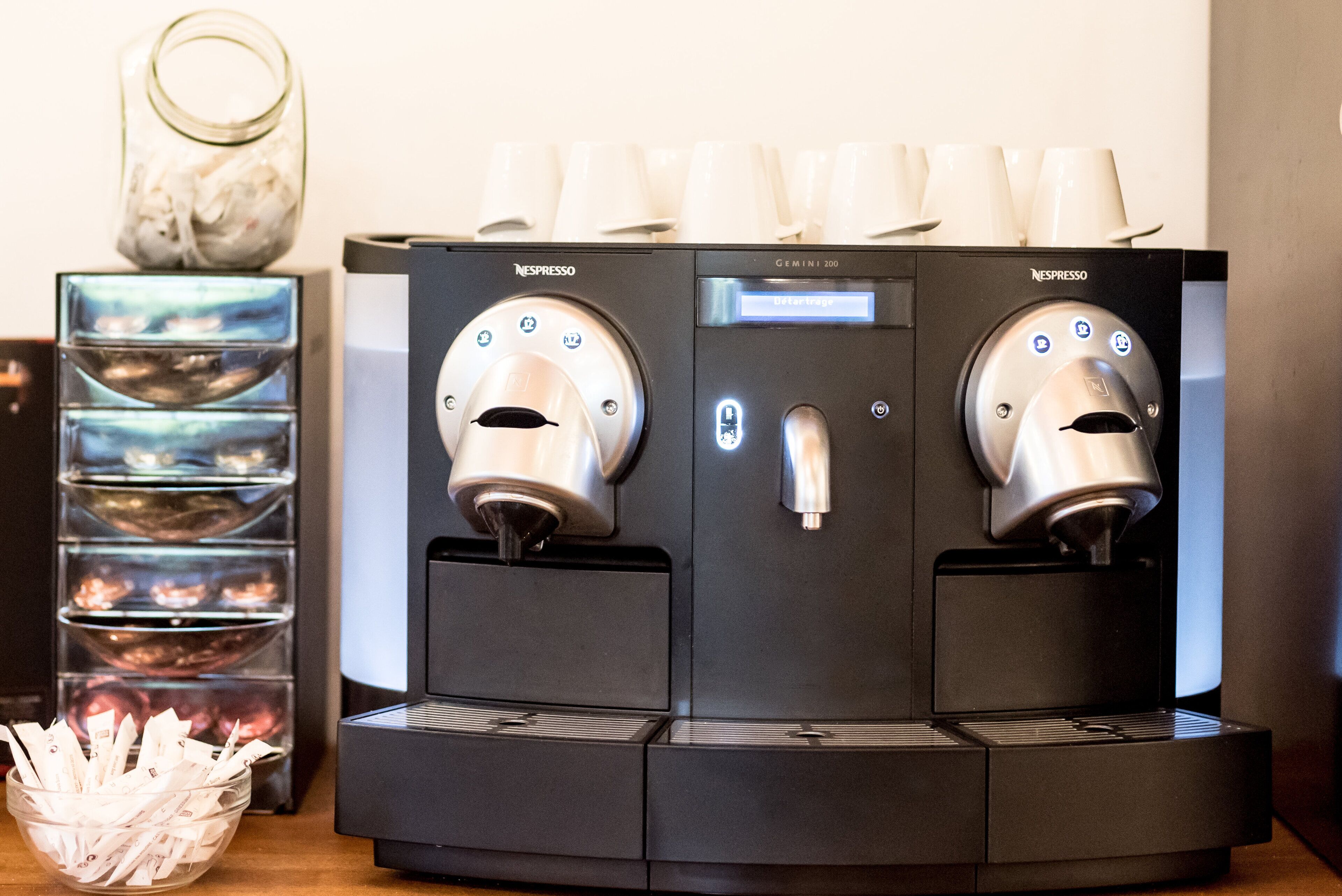 Two Nespresso coffee machines with a glass display and a basket of coffee pods.