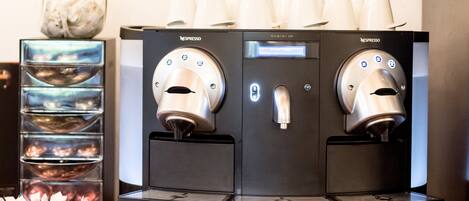 Two Nespresso coffee machines with a glass display and a basket of coffee pods.