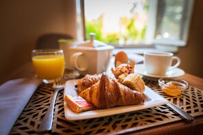 A breakfast table with croissants, a glass of orange juice, a teapot, a cup of coffee, and a small bowl of jam. - Cerise Carcassonne Sud (Carcassonne)