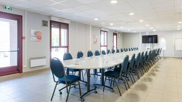 Una sala de conferències amb una taula llarga, cadires blaves i una pissarra.