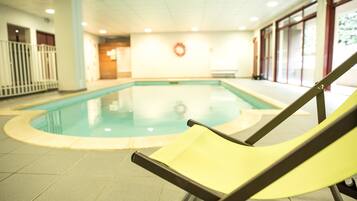 An indoor swimming pool with a yellow lounge chair in the foreground.