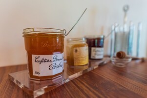 Un tarro de Confiture Bonne Pêche sobre una mesa de madera con una bandeja transparente.