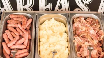 Três distribuidores de comida com salsichas, purê de batatas e bacon.