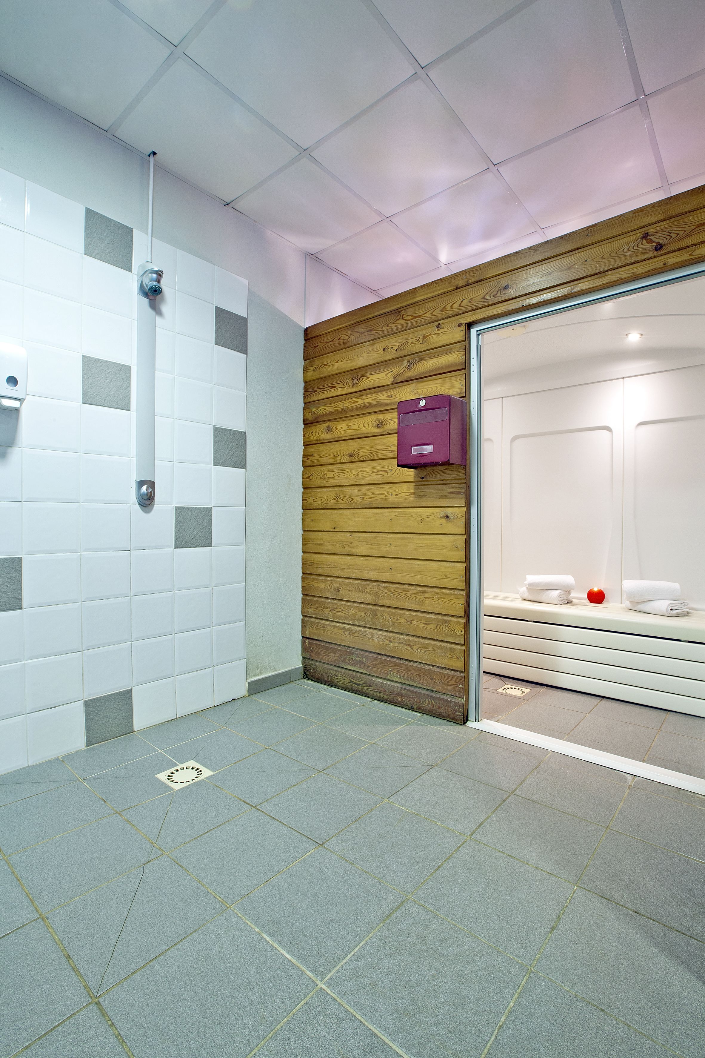 A public restroom with tiled walls, a wooden accent wall, and a bench with towels.