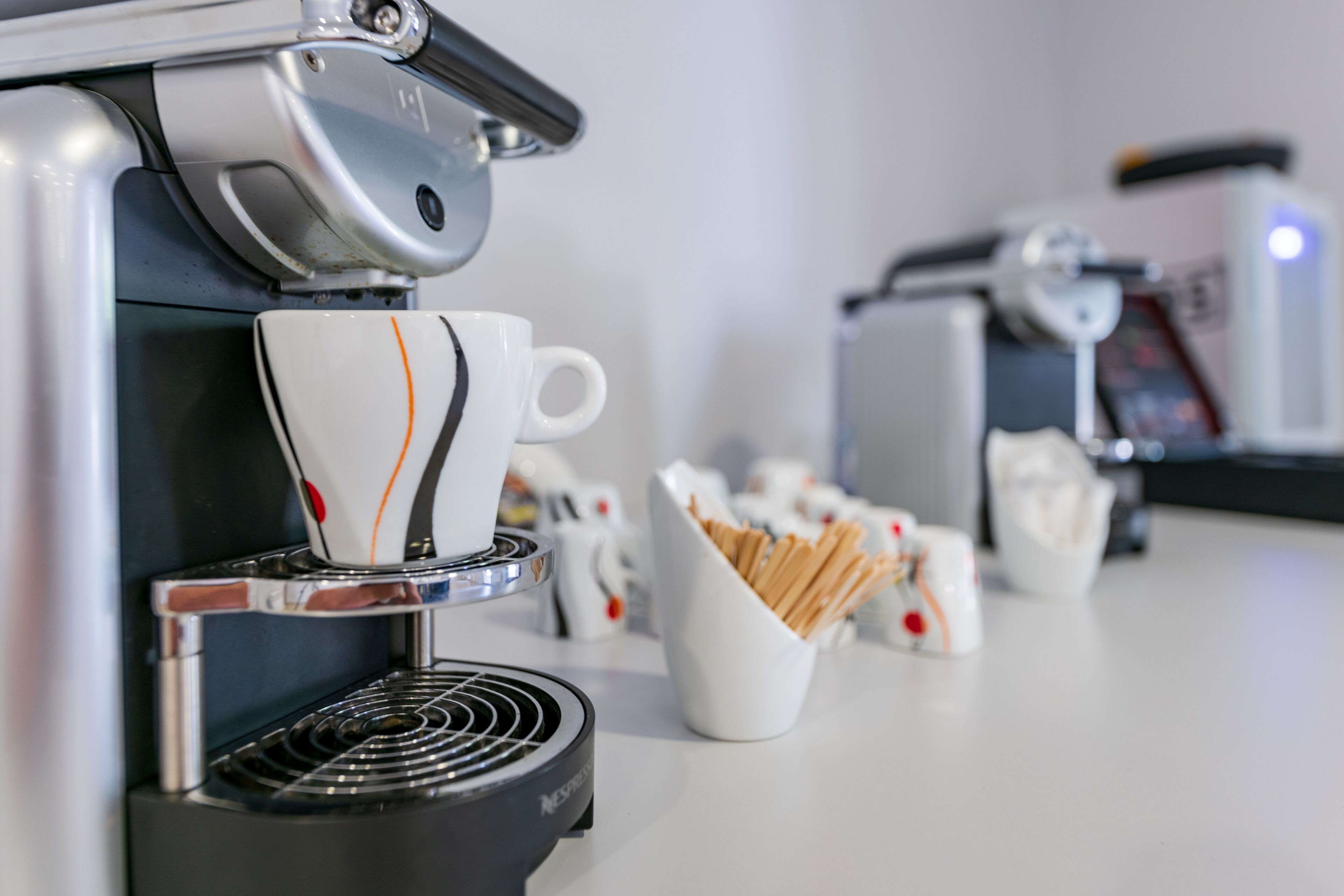 A coffee machine with a cup of coffee and a basket of biscotti.