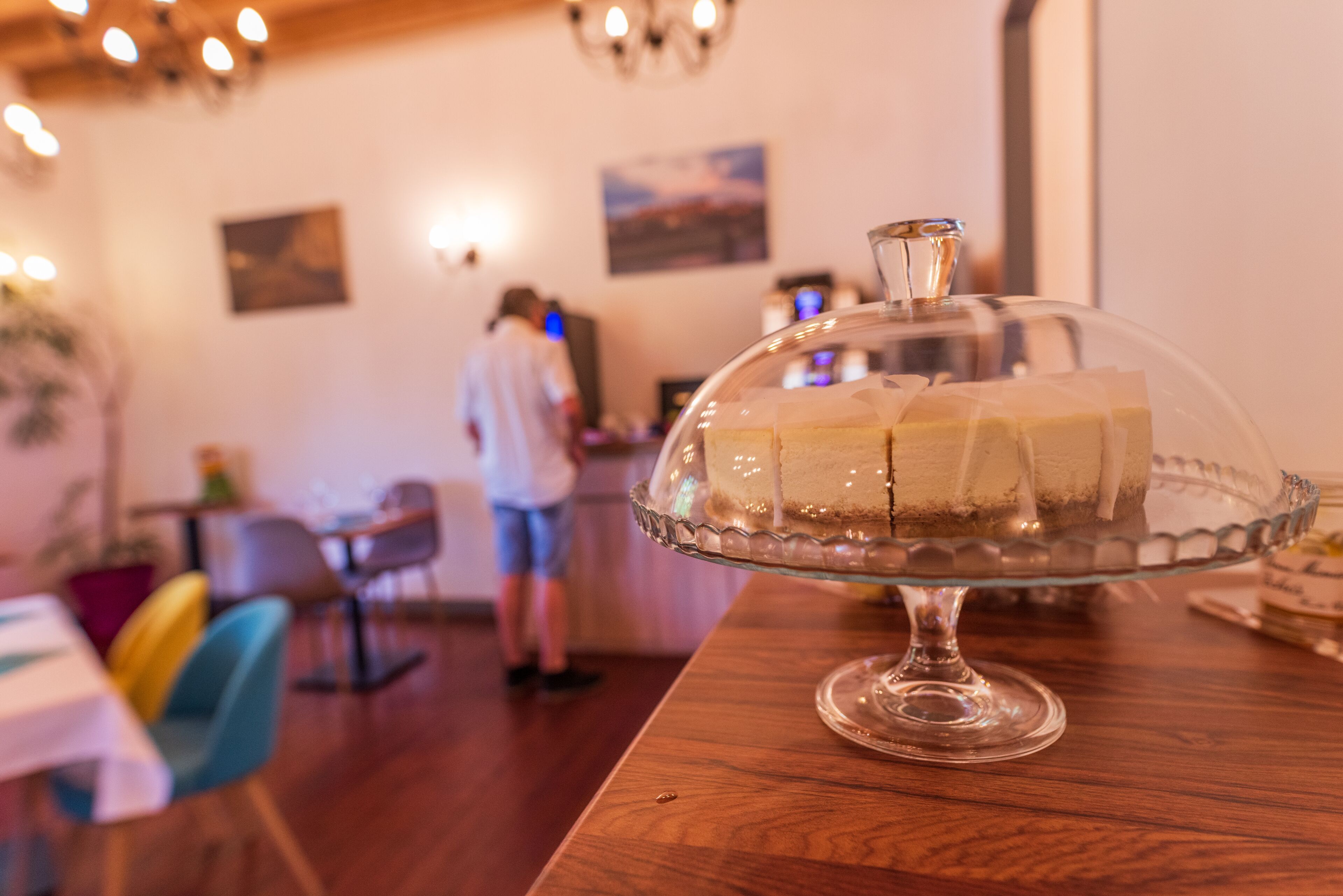 A dessert display with a glass dome on a wooden table in a restaurant.