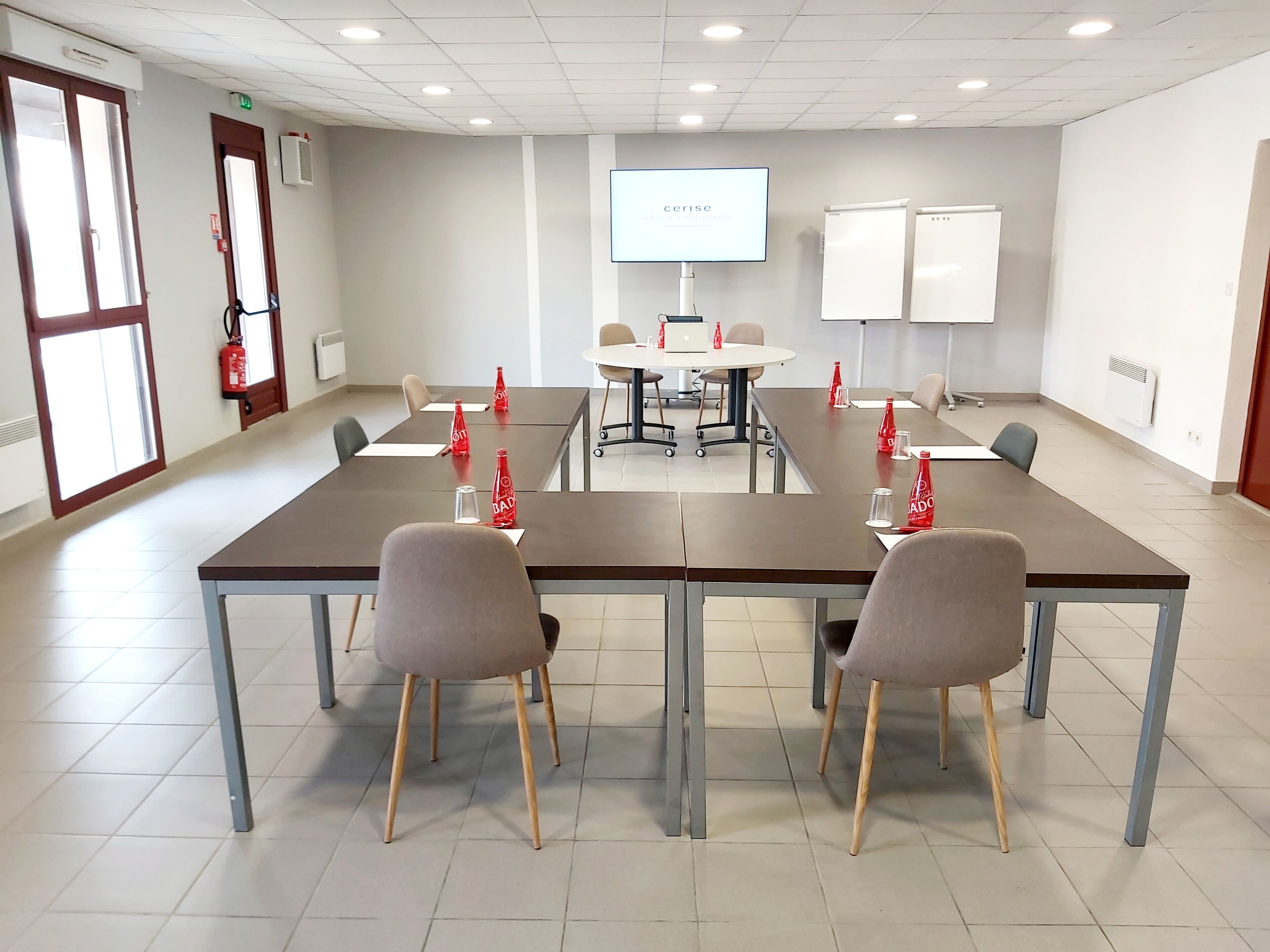 A conference room with a long table, chairs, a projector screen, and a whiteboard.
