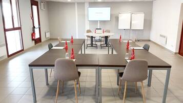 A conference room with a long table, chairs, a projector screen, and a whiteboard.