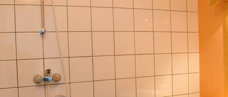 Un baño con ducha, lavabo y suelo de baldosas.