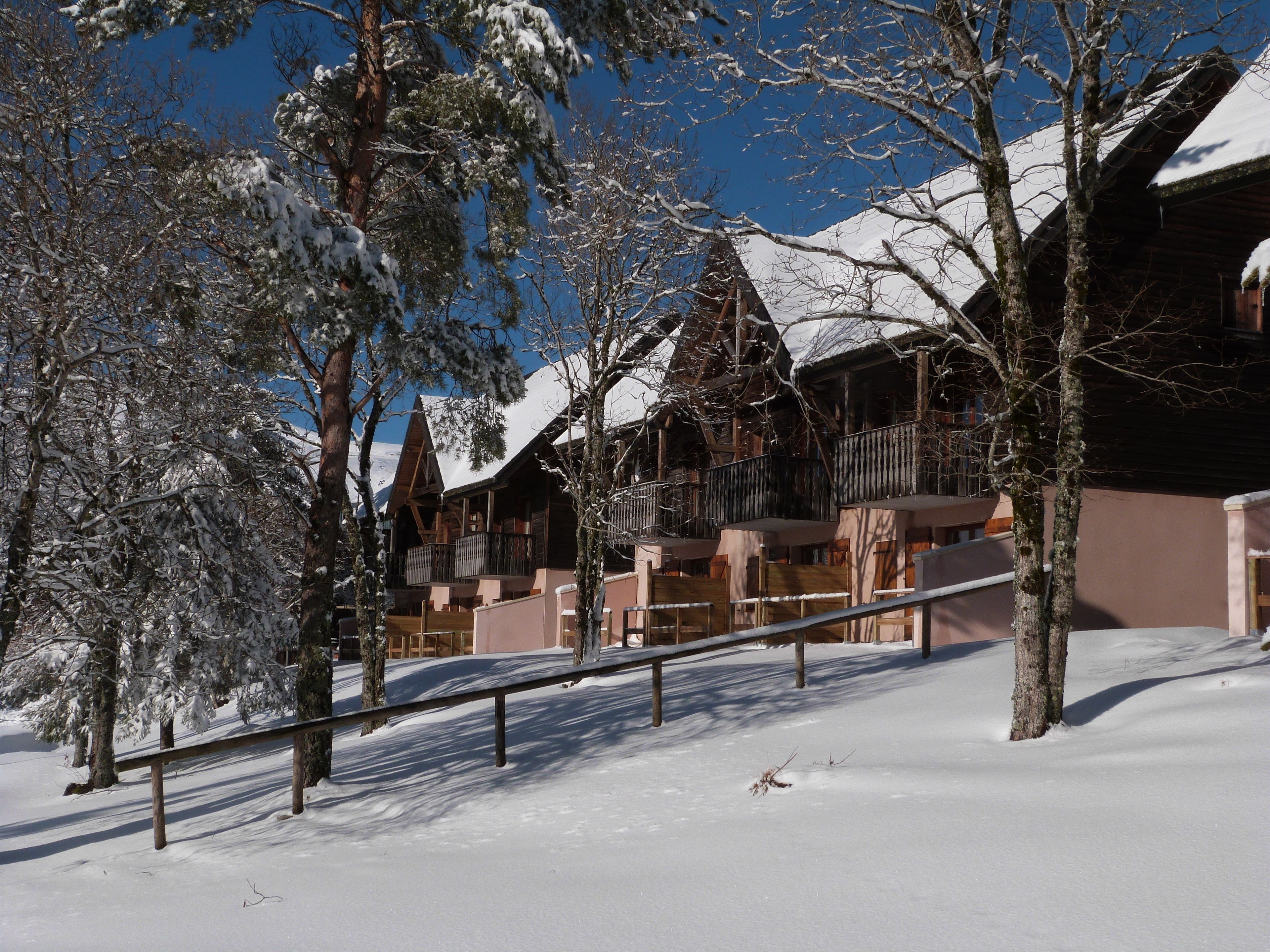 Un chalet enneigé doté de plusieurs balcons et d’une façade en bois.