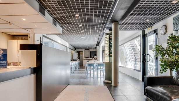 Un hall d’hôtel moderne comprenant un comptoir d’accueil, un espace salon et un escalier menant à l’étage supérieur.