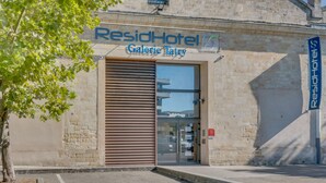 L’entrée d’un hôtel, avec une grande porte vitrée et une enseigne indiquant « ResidHotel Galerie Tatry ».