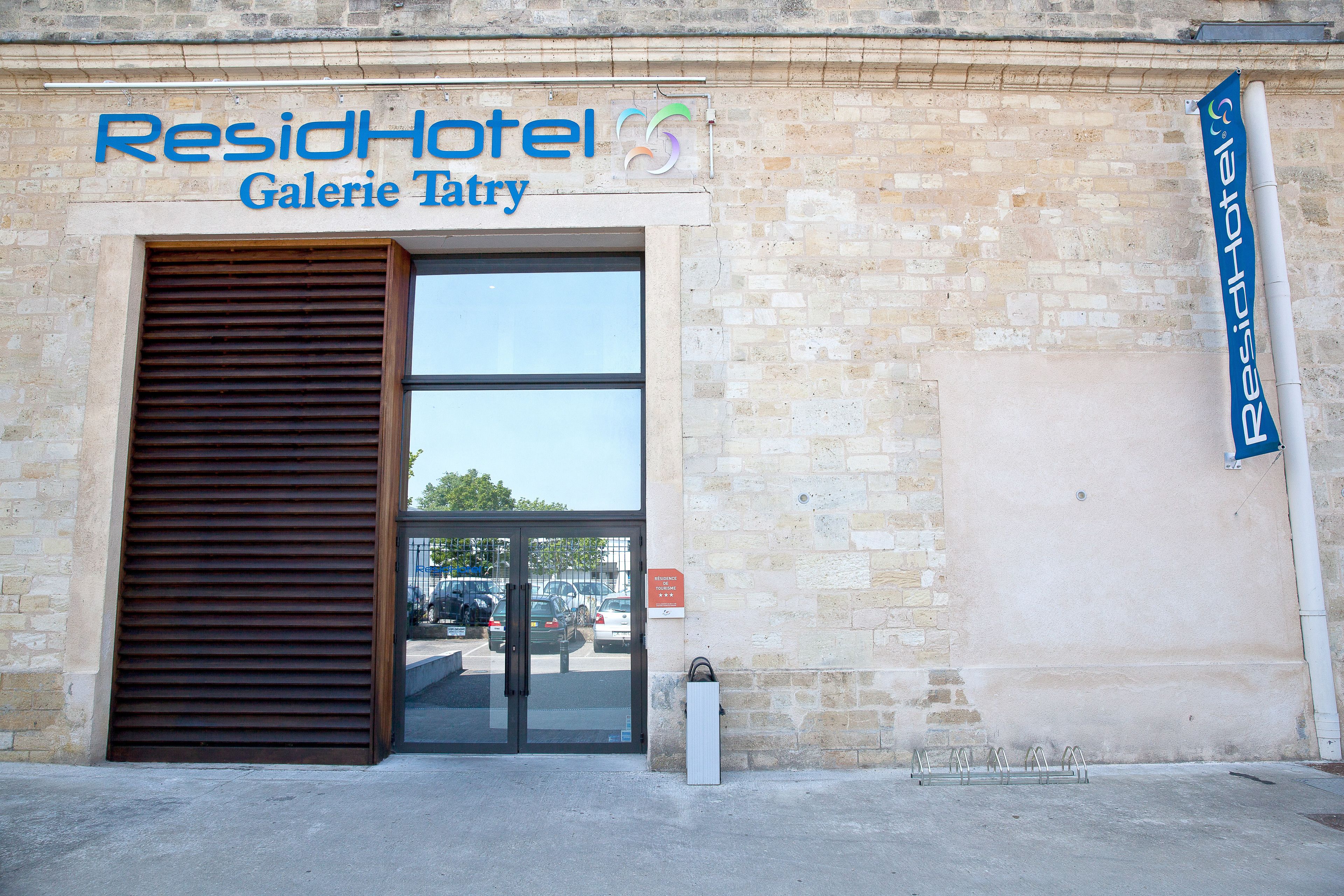 Entrada de un hotel con una gran puerta corrediza y un letrero encima.