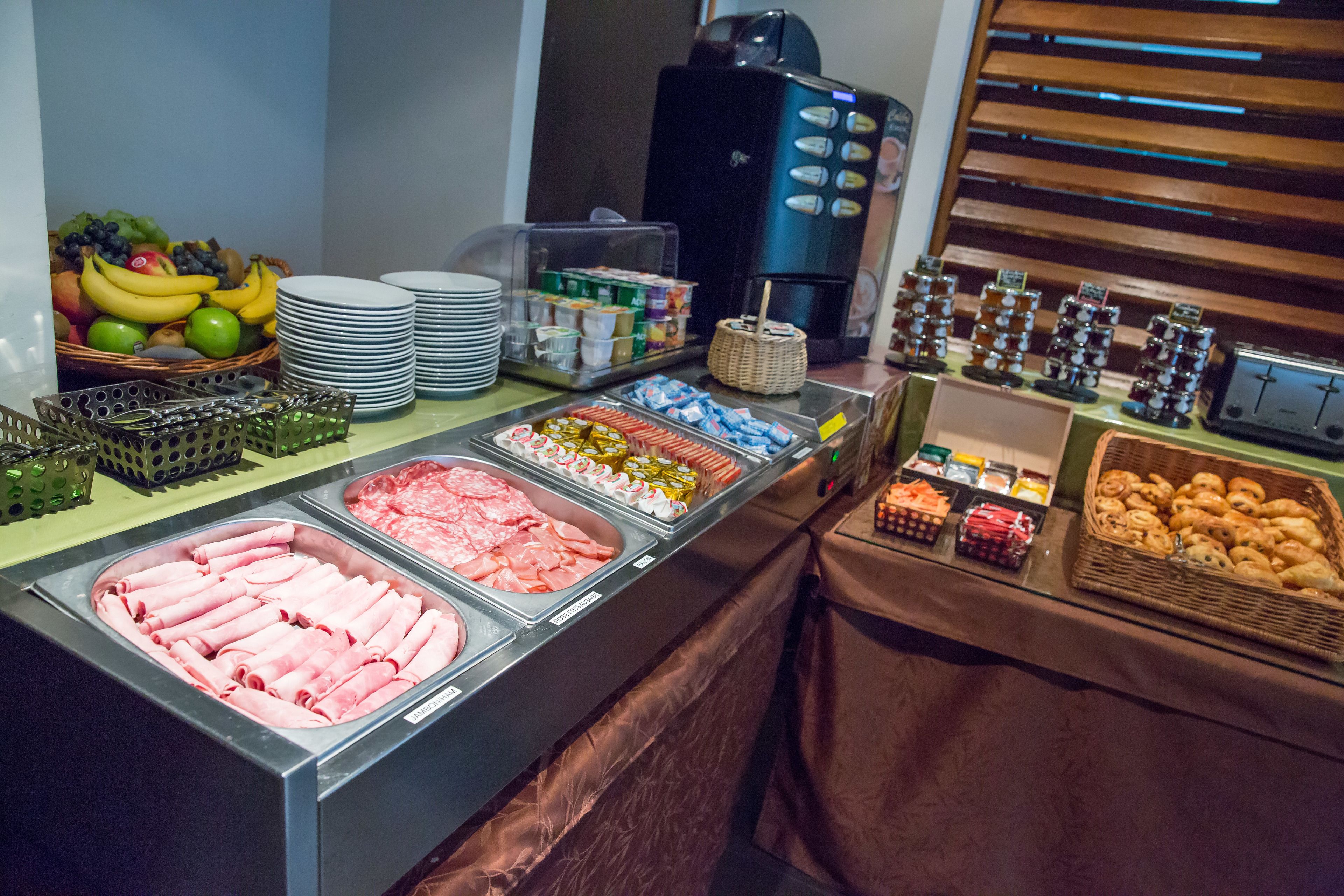 A buffet with various food options including meats, fruits, and pastries.