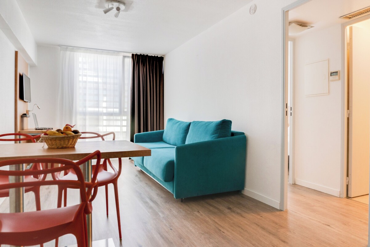 Un salon moderne avec un canapé de couleur turquoise, une table à manger en bois et des chaises rouges.