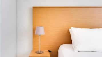 A hotel room with a wooden headboard, a bedside table with a lamp, and a white bed.