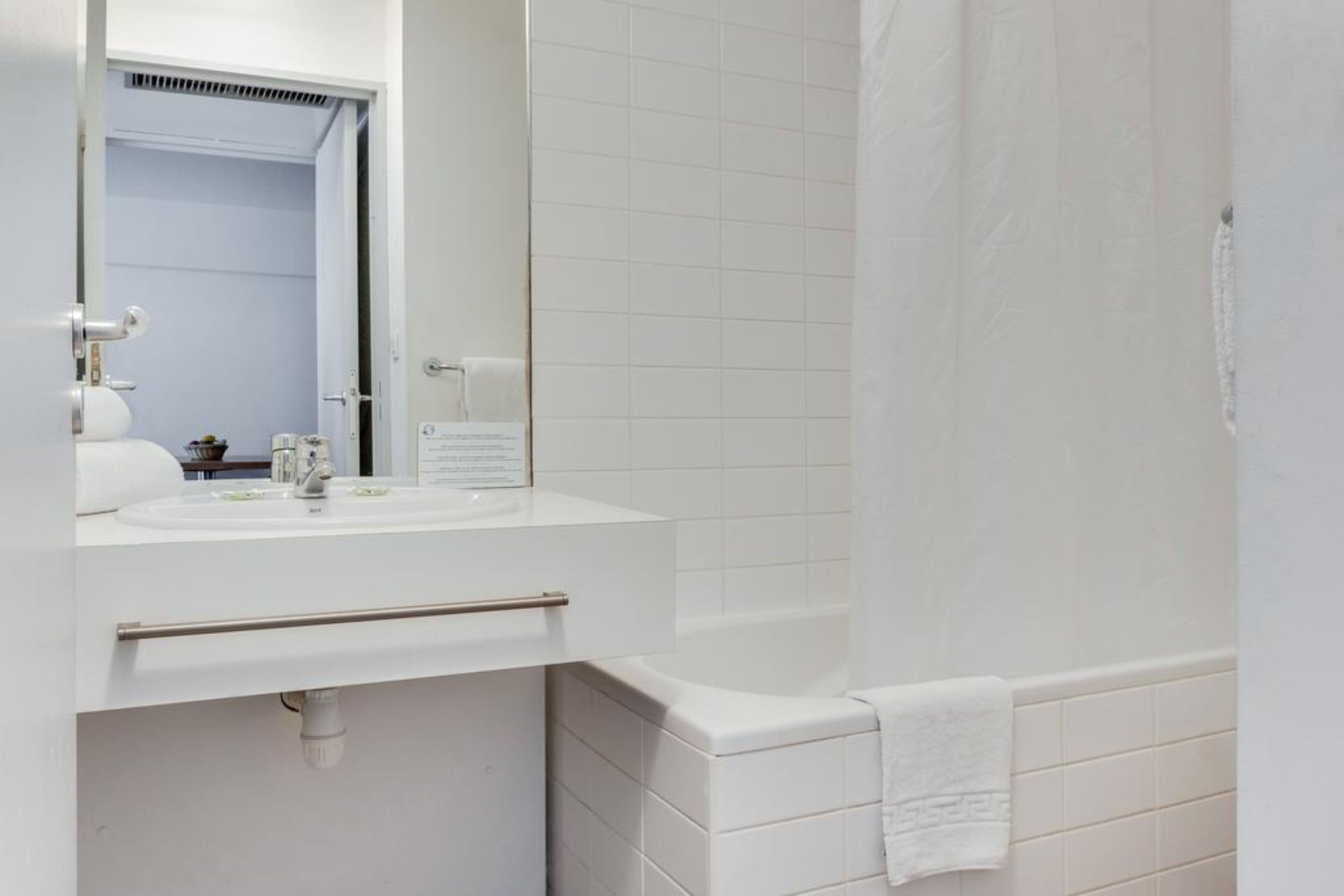 Un baño con lavamanos, espejo y bañera blancos.