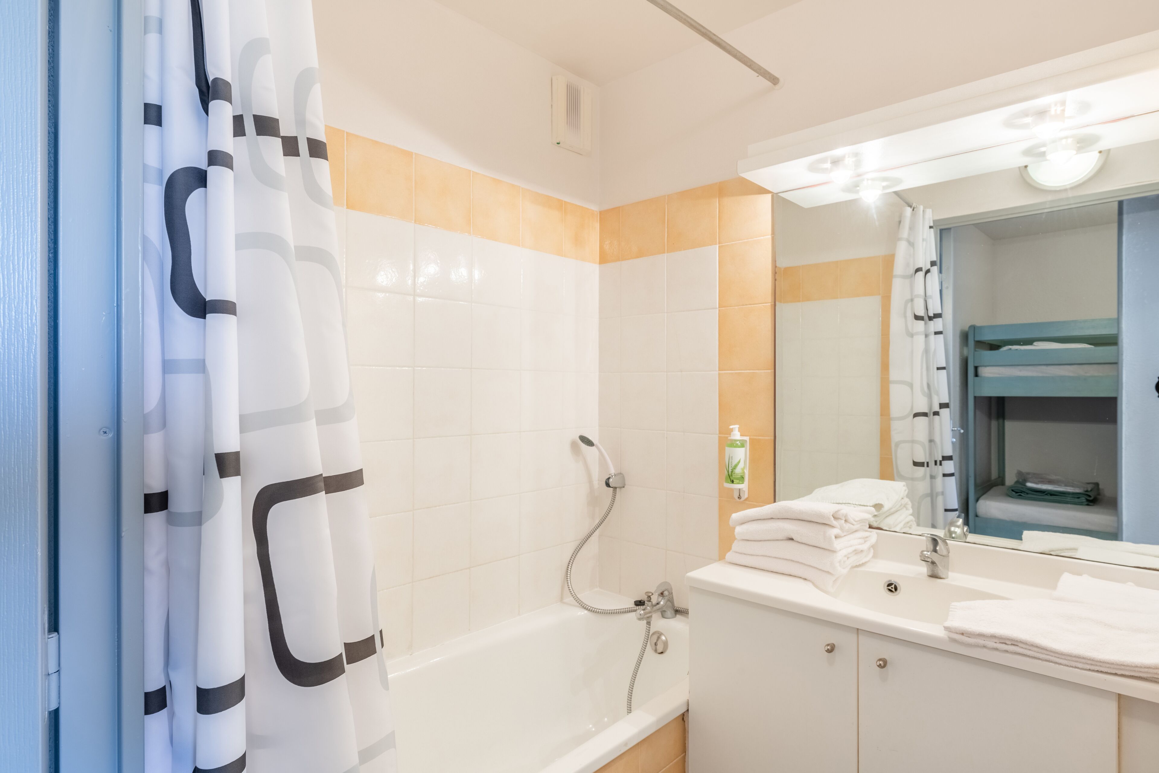 A bathroom with a bathtub, a sink, a mirror, and a towel rack.