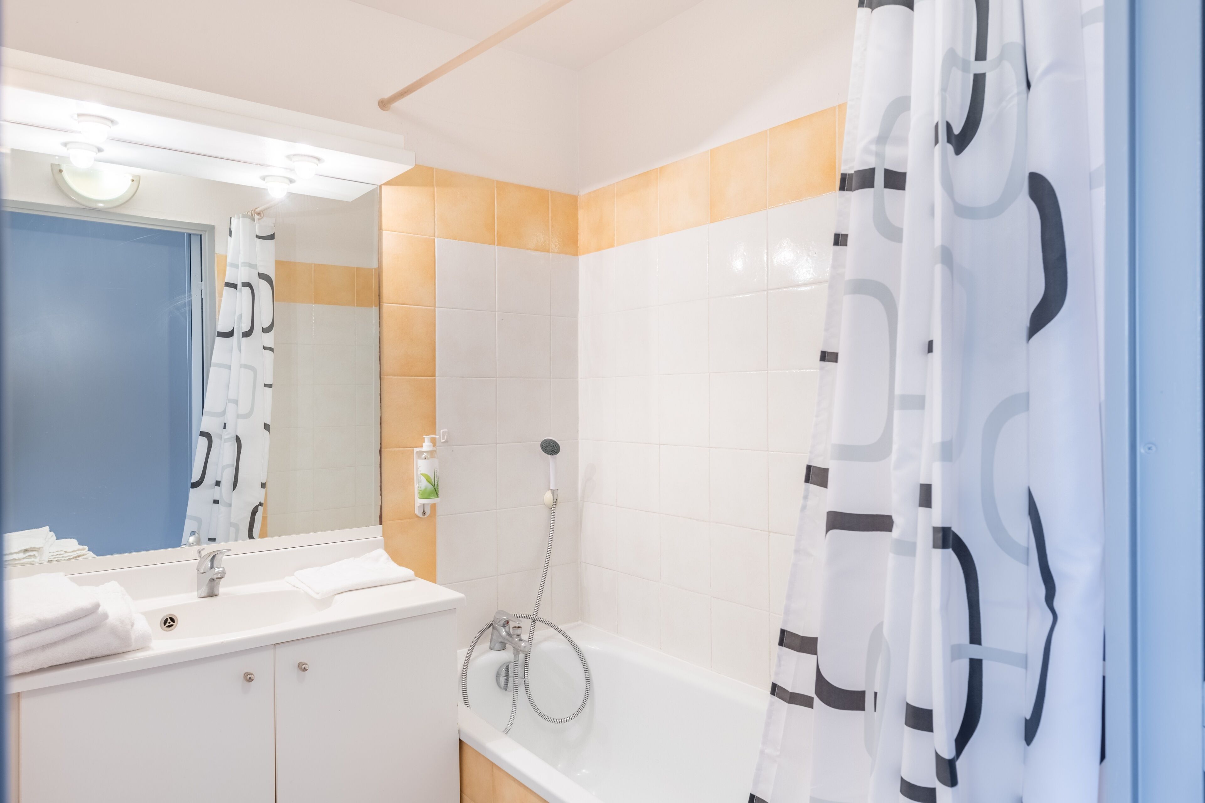 A bathroom with a white sink, mirror, and shower.