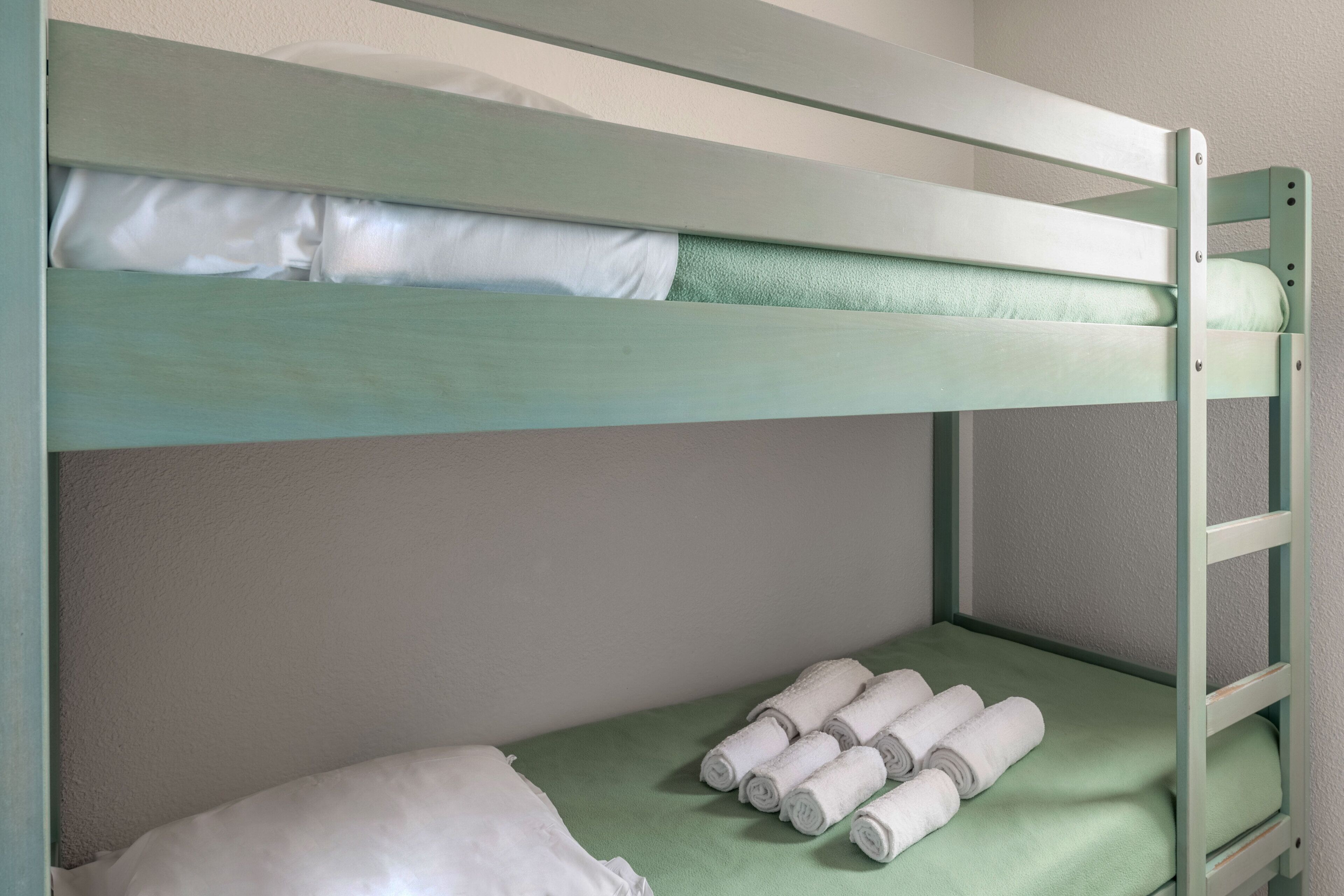 Una cama individual con ropa de cama verde y almohadas blancas.