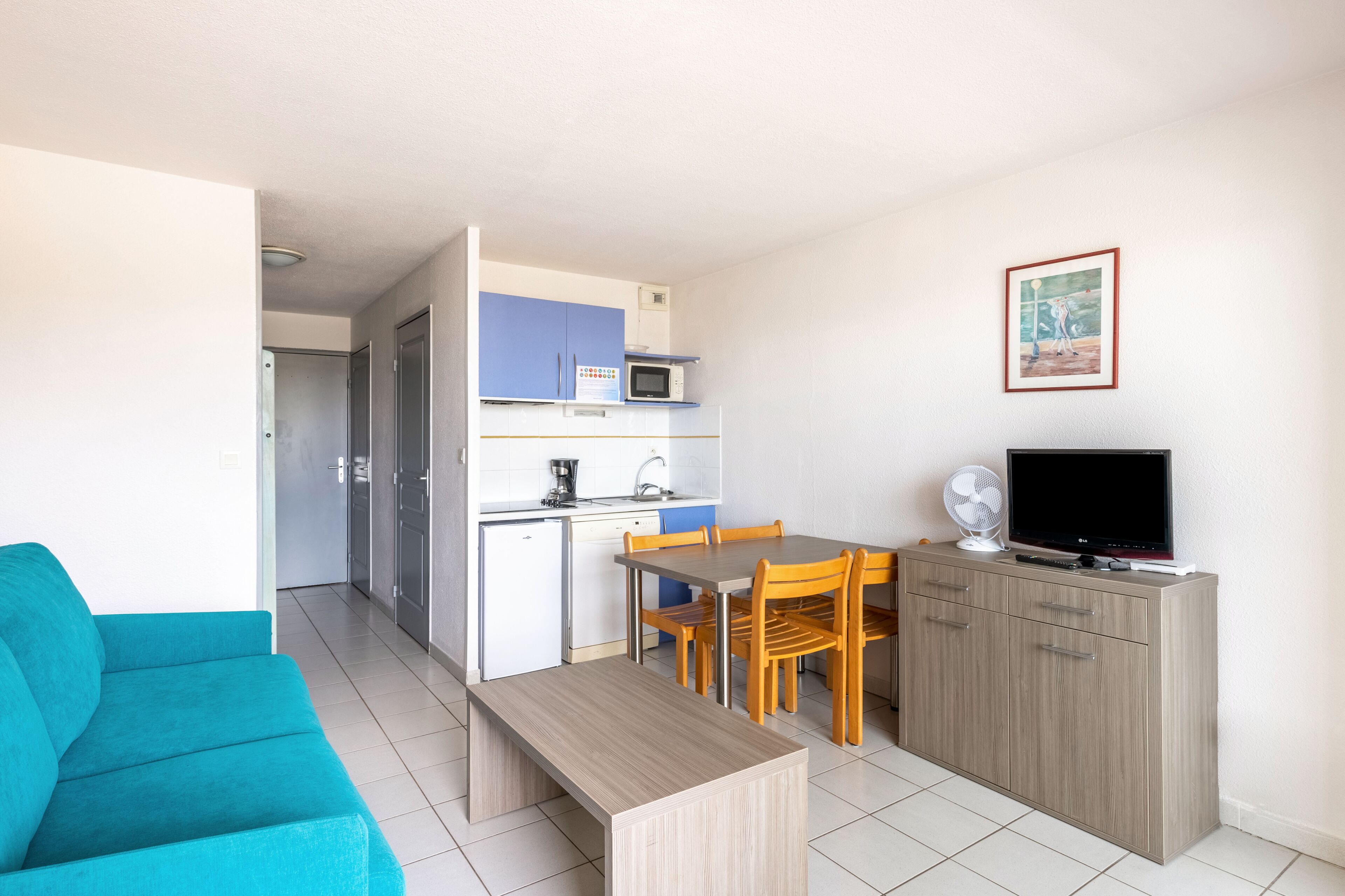 Un espacio habitable compacto con kitchenette, comedor y zona de estar.